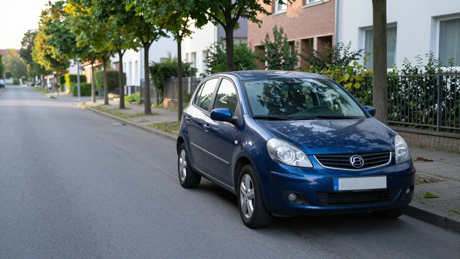 Ein dunkelblauer Kompaktwagen parkt am frühen Morgen in einer ruhigen Wohnstraße mit Bäumen